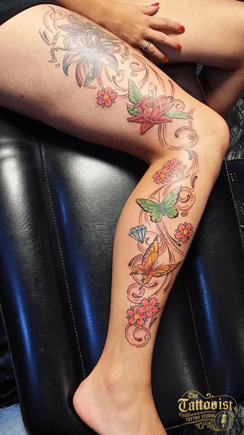 Kleurrijke bloemen, vlinders en krullen die van heup tot enkel over een been doorlopen.