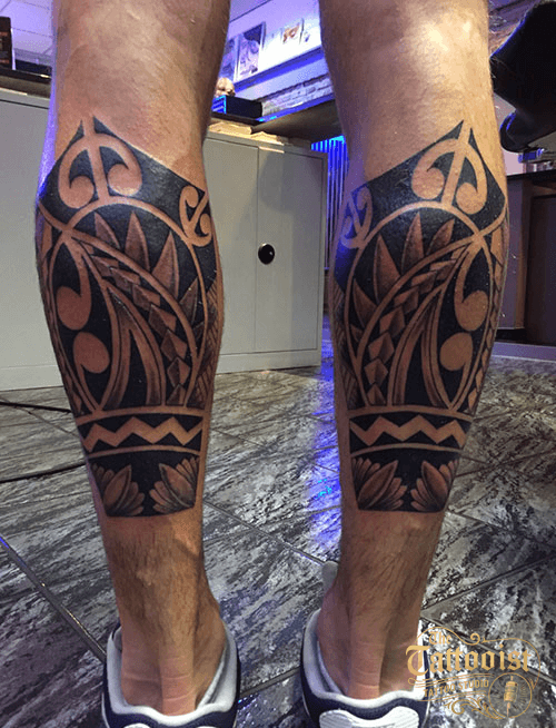 Twee kuiten met zwart Maori- en tribalwerk dat over de kuitspier doorloopt.